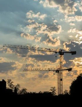 Two cranes at sunset at the construction site Stock Photos