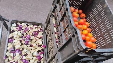 Two crates, one containing chopped eggplants and the other containing tomatoes. Stock Photos