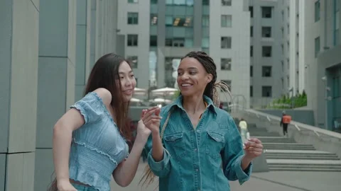 Two crazy asian and mixed race girls dancing and fooling around outdoors Stock Footage 159787754