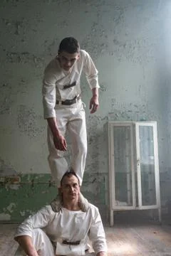 Two crazy men in straitjackets are in an abandoned clinic Stock Photos