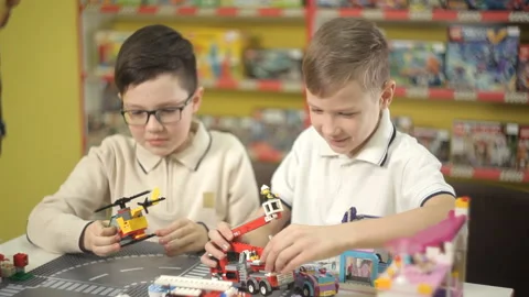 Two creative boys build from the cubes of the designer various objects Stock Footage 87958562
