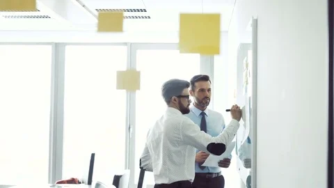 Two creative businessmen working on whiteboard at modern office Stock Footage 73672653