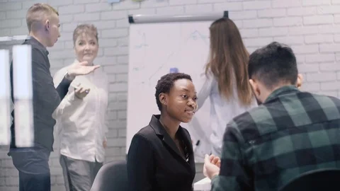 Two creative minds talking while its other partners work on the white board. Stock Footage 120767437