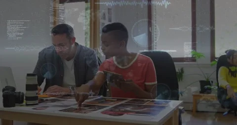 Two creatives tapping tablet and reviewing prints, camera visible, animated Stock Footage 330380089
