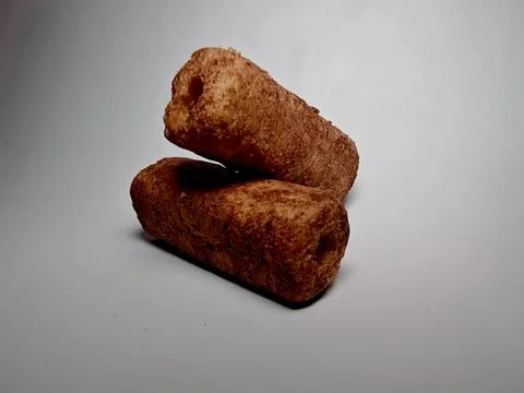 Two crispy brown corn snack rolls stacked on a white background 库存照片