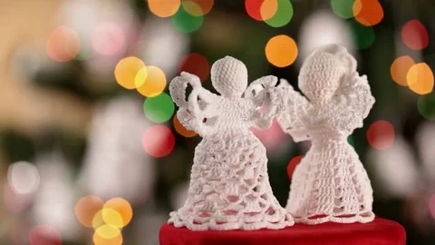 Two crocheted xmas angel decorations spinning in front of christmas tree Видео 80909211