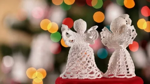 Two crocheted xmas angels decorations in front of christmas tree Video stock 81133865