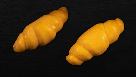 Two Croissants baking timelapse, dark slate board background Vídeos de archivo 105395144
