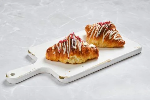 Two croissants with raspberry jam on white board on marble background Stock Photos