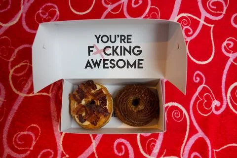 Two cronuts in a paper box on a red background. Stock Photos