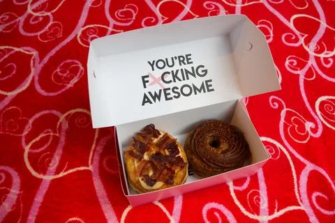 Two cronuts in a paper box on a red background. Stock Photos