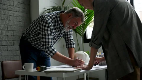 Two cropped architects discussing floor plan at table in office Video stock 231486522