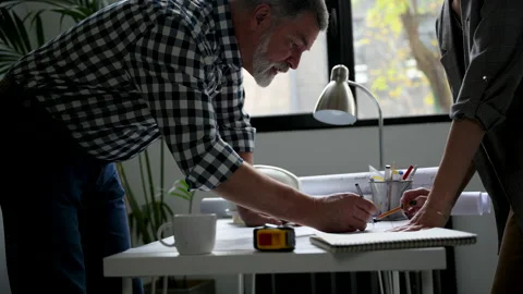 Two cropped architects discussing floor plan at table in office Stock Footage 231486737