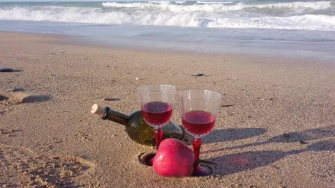 Two crystal glasses with red wine stand on sand. glass wine bottle. Red Apple Stock Footage 144108342