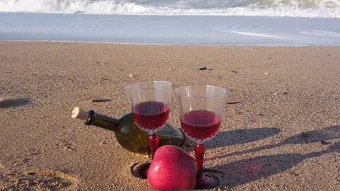 Two crystal glasses with red wine stand on sand. glass wine bottle. Red Apple Stock Footage 144108343