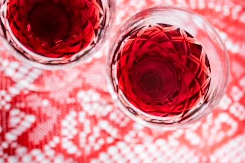 Two crystal glasses of red wine, red background, closeup. Stock Photos