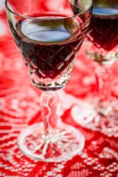 Two crystal glasses of red wine, red background, closeup. Stock Photos