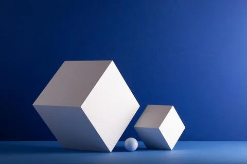 Two cubes with white golf ball on the blue background. 库存照片