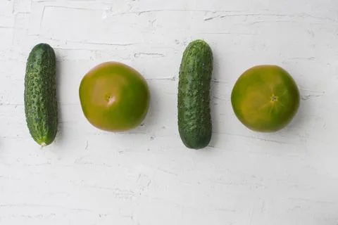 Two cucumbers and two tomatoes lie on a white concrete background. 写真素材