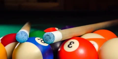 Two cues lie on a triangle with billiard balls on the pool table Stock-Fotos