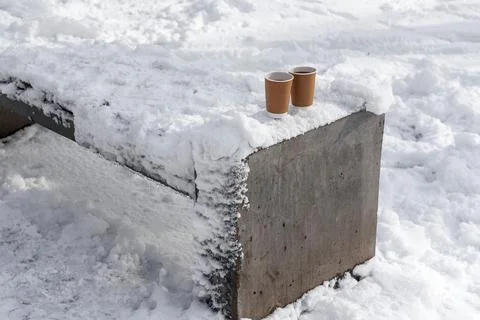 Two cup coffee or tea to go on snowcowered bench. Two takeaway paper cups with Stock Photos