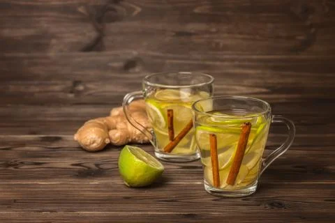 Two cup of soothing tea with ginger, lime and cinnamon on wooden background,  写真素材