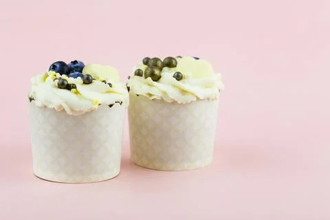 Two cupcakes on a pink background. Pair of cupcakes for lovers on a pink Stock Photos