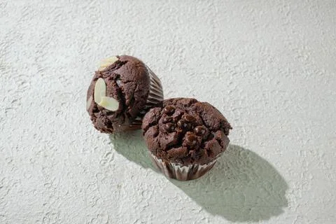 Two of cupcakes on textured white: one chocolate with chocochips and one ch.. Stock Photos