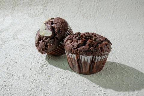 Two of cupcakes on textured white: one chocolate with chocochips and one ch.. Stock Photos