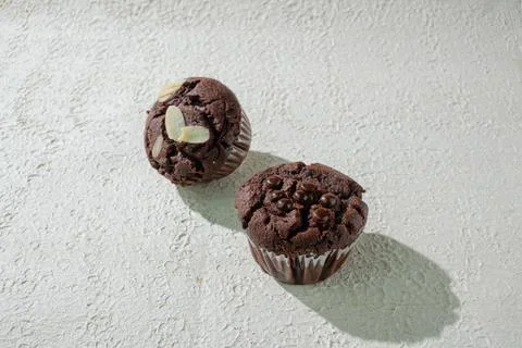 Two of cupcakes on textured white: one chocolate with chocochips and one ch.. Stock Photos