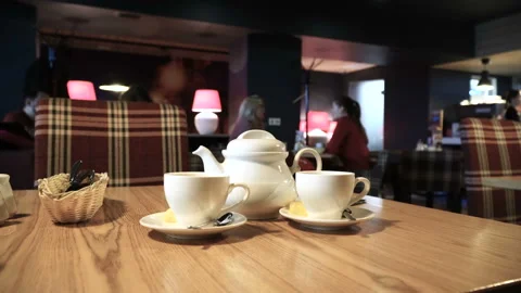 Two cups and teapot at cafe table. Blurred people background. Cafe interior 4k Stock-Footage 89021237