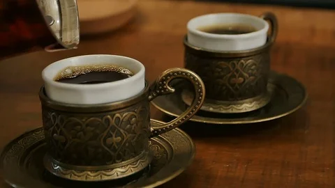 Two cups of black coffee being poured from a turk Vidéo 75445348