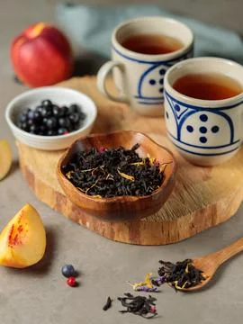 Two cups of black tea with pieces of fruit and berries on a slab. Vertical Stock Photos