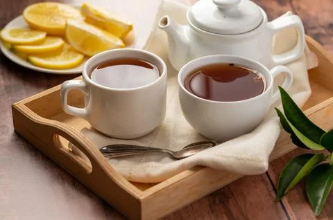 Two cups of black tea, tea pot and lemon slices. Tea time. Stock-Fotos