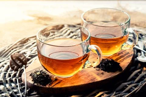 Two cups of black tea on a wicker table early in the morning, closeup. Tea mo Stock Photos