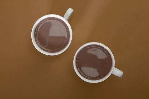 Two cups with brown liquid on a flat surface during a bright morning Stock Photos
