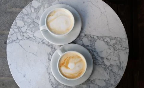 Two cups of cappuccino or latte decorated with foam on marble table background Stock Photos