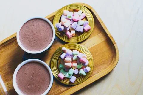 Two cups of cocoa with multicolored marshmallow on  a golden saucers. Stock Photos