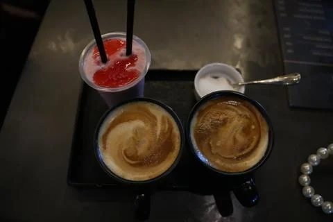 Two Cups of Coffee and Red Fruit Drink on a Cafe Table Stock Photos
