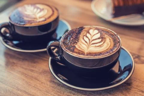 Two cups of coffee with art on a table Stock Photos