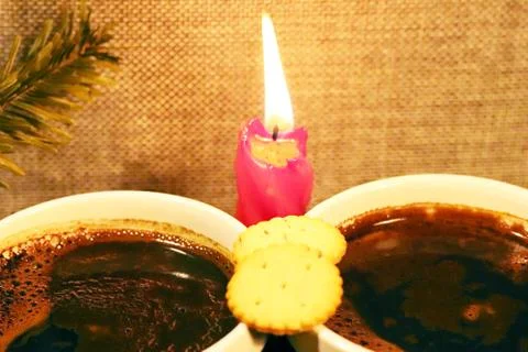 Two cups with coffee on the background of a red candle and a sprig of spruce. Stock Photos