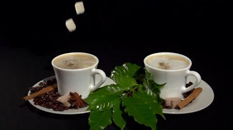 Two cups of coffee on a black background. A sugar cube falls in a cup of coffee. Video stock 61197625