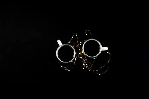 Two cups with coffee on black table with christmas lights. Photograph taken f Stock Photos