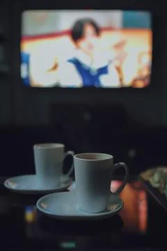 Two cups of coffee in front of the TV in a quiet and romantic atmosphere Stock Photos