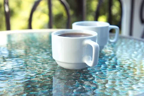 Two cups of coffee on a glass table on an open terrace Stock Photos