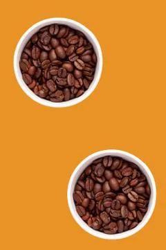 Two cups with coffee grains, flatlay, orange background, vertical, cutout. Stock Photos