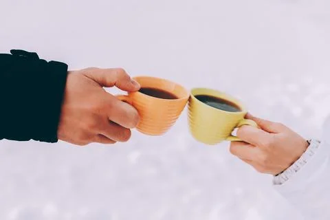 Two cups of coffee in the hands of happy couple. Winter theme Stock Photos