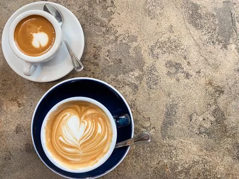 Two cups of coffee with latte art on stone background with copy space Stock Photos