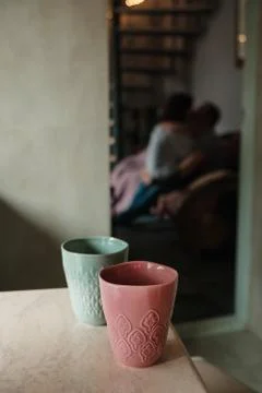 Two cups of coffee on stone table with a romantic couple in background Stock Photos