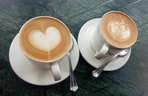 A two cups of coffee on a table with latte art heart and leaf Foto stock